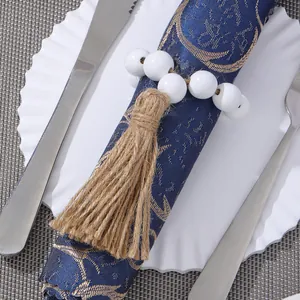 Detail of wooden beads napkin ring with jute tassel on elegant blue fabric