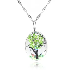 Gros plan du pendentif ovale en verre avec fleurs séchées vertes et motif papillon