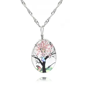 Vue macro d'un pendentif ovale en verre avec fleurs séchées roses sur une chaîne argent