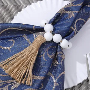 Detail of handmade wood bead napkin ring with rustic jute tassel on a blue fabric