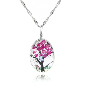 Détail du collier pendentif ovale en verre avec fleurs séchées roses et motif papillon