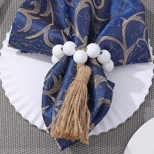 Close-up of a white bead napkin ring with a natural hemp tassel on a blue cloth