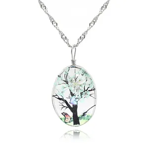 Vue macro du pendentif ovale arbre de vie avec fleurs bleues et détail papillon