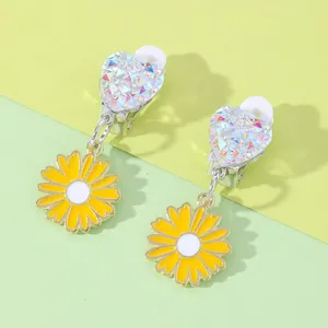 Detail of heart-shaped clip-on earrings with yellow daisy pendants and soft pads