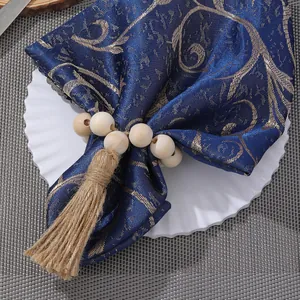 Bohemian wood bead napkin rings with jute tassels on elegant blue patterned table linen