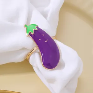 Dettaglio di un portatovagliolo a forma di melanzana viola con foglie su lino bianco