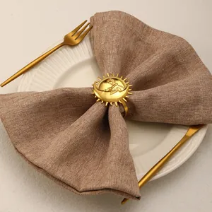 Detailed close-up of golden sun and moon alloy napkin ring on a brown linen cloth