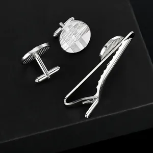 Close-up of silver geometric textured cufflinks and tie clip set in a premium black gift box