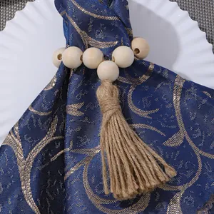 Close-up of wood bead napkin ring with jute tassel on a navy blue jacquard cloth