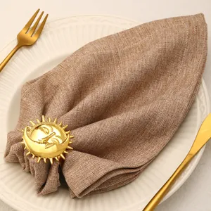 Close-up of golden sun and moon napkin ring on a beige linen napkin with elegant dinnerware