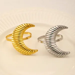 Golden and silver crescent moon napkin rings with textured wave patterns on white porcelain plate