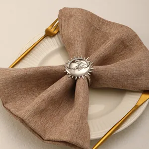 Close-up of silver metal sun and moon napkin ring on a plate with elegant gold cutlery