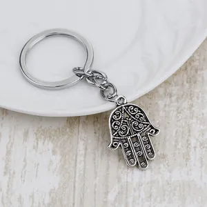 Detail of vintage silver Hamsa Hand keychain with intricate hollow filigree on white ceramic