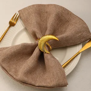 Close-up of golden crescent napkin ring with radial texture on a linen napkin