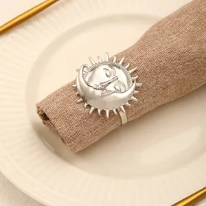 Detail of silver sun and moon alloy napkin ring on a brown linen napkin with tableware