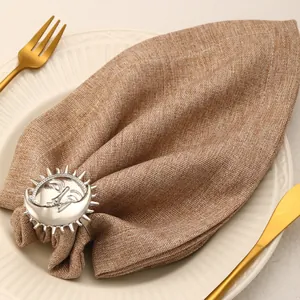 Detailed view of a silver sun and moon napkin ring on a brown linen napkin with cutlery
