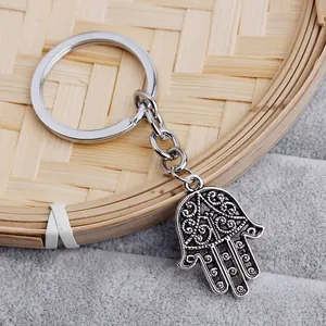 Detail of silver Hamsa hand keychain with hollow carving on a bamboo woven tray