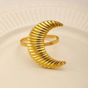Detail of gold crescent moon napkin ring with wavy texture on white ceramic plate