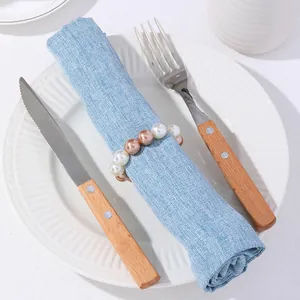 Detalle de servilletero con perlas champán sobre servilleta de lino en mesa elegante