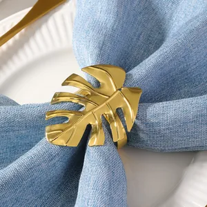 Servilletero dorado con forma de hoja de Monstera sobre servilleta de lino azul