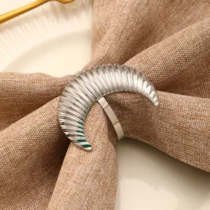 Silver crescent moon napkin ring with radial fluting on linen fabric and white ceramic plate