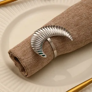 Detailed view of silver moon napkin ring with spiral texture on white ceramic plate
