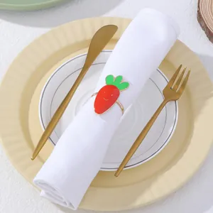 Dettaglio del portatovagliolo a carota dorata con smalto rosso su un tovagliolo bianco