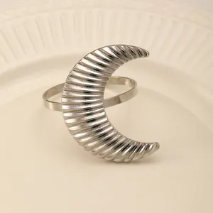 Close-up of a silver crescent moon napkin ring with textured stripes on a white plate
