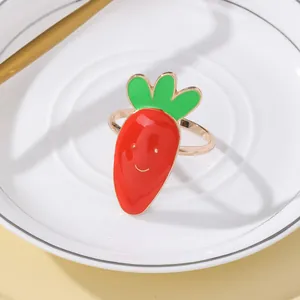 Dettaglio di un portatovagliolo a carota in lega con smalto colorato su un piatto bianco