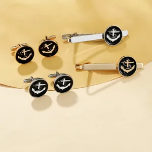 Detailed set of gold and silver nautical anchor cufflinks and tie clips on matte surface