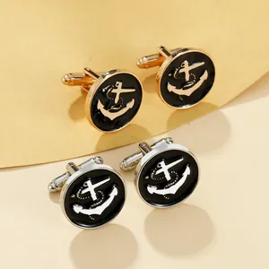 Detailed view of silver and gold anchor cufflinks with black enamel on a neutral background