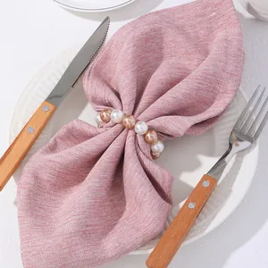 Anillo de servilleta de perlas champán y blancas en lino rosa para decoración de mesa