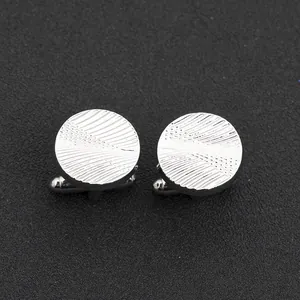 Macro view of silver round cufflinks with detailed radial pattern and T-shaped swivel clasp