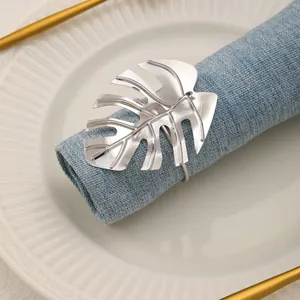 Servilletero de hoja de Monstera plateado en una elegante mesa con servilleta azul.