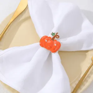Dettaglio dell'anello portatovagliolo a zucca su tovagliolo bianco e piatto in ceramica beige