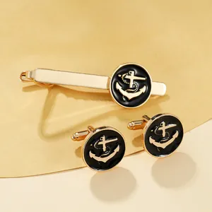 Detailed view of gold anchor cufflinks and tie clip set with black enamel inlay