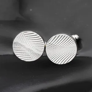Classic round silver cufflinks with radial spiral texture on a black background
