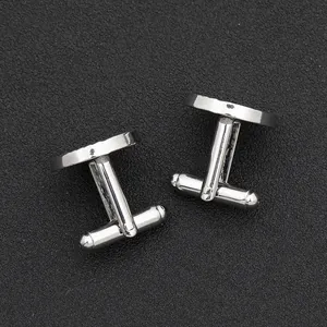 Detail of silver round cufflinks with spiral pattern on black matte background