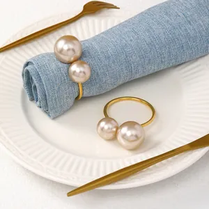 Dettaglio elegante portatovagliolo a U dorato con due perle di dimensioni diverse su tavola