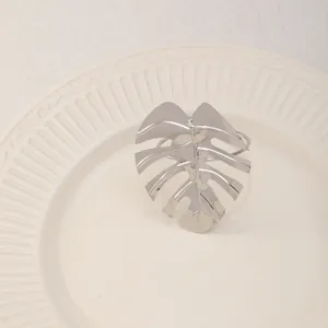 Servilletero de hoja de monstera plateada en plato de cerámica blanca decorativo mesa