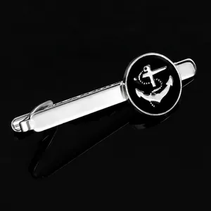 Detail of silver tie clip with black circular anchor emblem on black reflective surface