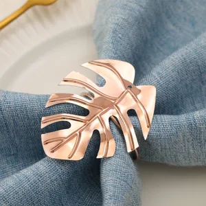 Elegante servilletero de oro rosa con diseño de hoja de Monstera sobre lino azul