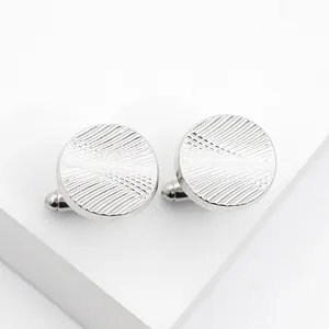 Detailed macro view of silver round cufflinks with sunburst radial engraved texture