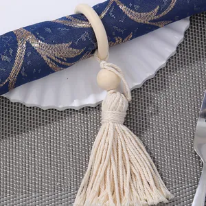 Portatovaglioli con perline di legno e nappa su tovagliolo blu e piatto bianco decorato