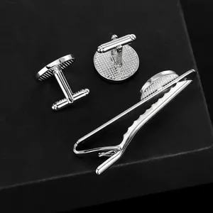 Detailed close-up of silver anchor cufflinks and tie clip set on a dark textured background