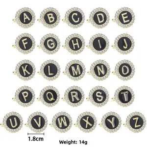 Detailed grid of gold finish rings with black enamel, crystal accents, and A-Z alphabets