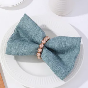 Anillo de servilleta con perlas champán sobre lino azul claro para decoración de mesas