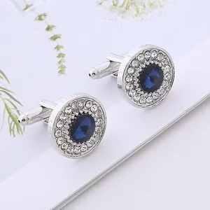 Macro detail of round silver cufflinks featuring a deep blue crystal and white zircon border