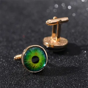 Dettaglio macro dei gemelli dorati con cabochon in vetro con occhio del diavolo verde