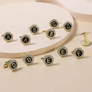 Close-up of gold-plated letter cufflinks with black enamel and crystal diamond border